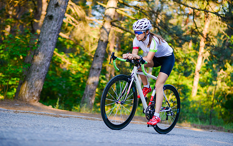 青年女赛车手骑着路自行车在夏日热火的森林中走免费道路 健康生活方式概念自由速度城市女孩成人森林公园爱好晴天女性图片