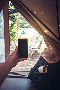 在露营帐篷里拿着电话的男人的手树木男性旅游视角闲暇技术娱乐太阳冒险成人图片