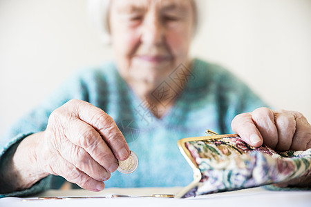 坐在桌边的关心她的老年妇女在钱包里数钱 笑声养老金退休金融现金账单商业孤独女士硬币女性图片