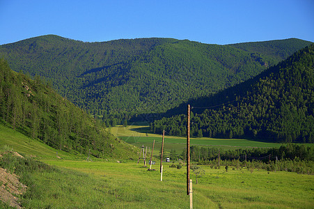 电线的木极穿过一个充满了山脉的肥沃山谷 阿尔泰西伯利亚俄罗斯 景观图片