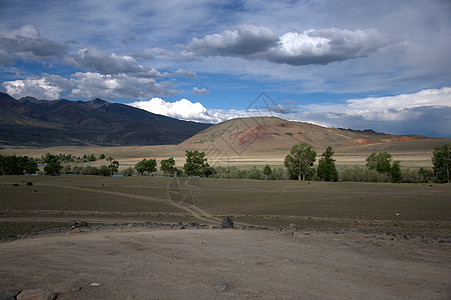 泥土路穿过大草原 通向山脚 以红色涂成岩石中含汞的红色 阿尔泰 西伯利亚 俄罗斯和风景图片