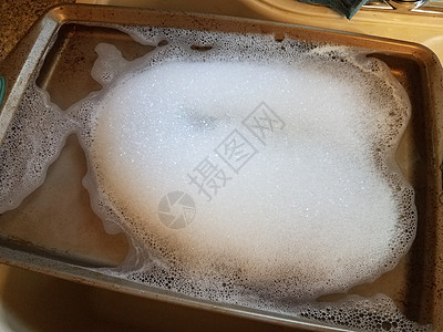 大力泼水和泡沫厨房水槽中带肥皂和水的金属烤盘泡沫打扫床单烘烤气泡托盘洗涤背景