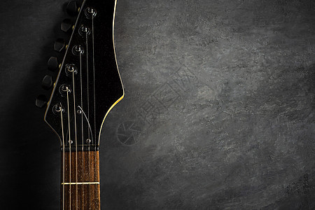 黑水泥地板上黑色电吉他的头头 最上面的六图片