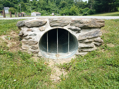 含有岩石 道路和草地的金属排水管道图片