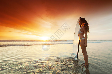 日落时在海滩上撒泡女人海洋热带天空旅行木板太阳运动冲浪冲浪者游泳衣图片