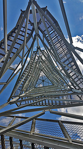 从下面通过塔上的金属烧烤炉查看下方情况建筑学扶手草地楼梯网格阳光建造建筑栏杆正方形图片