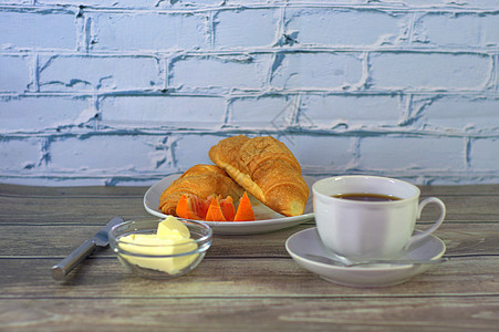 传统的早餐 一杯黑咖啡 两块羊角面包加黄油和橙色切片图片