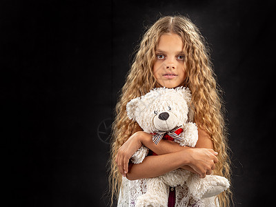 一个拥抱老小玩具熊的少女的肖像图片