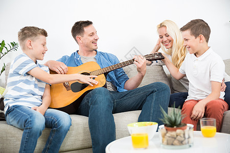 欢乐的caucaosian家庭微笑 在舒适的现代家一起弹吉他和唱歌旋律房间母亲沙发成人歌曲孩子客厅男人女士图片