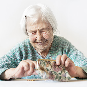 在家桌边坐着的96岁的老年妇女在支付帐单后对钱包中的养恤金储蓄感到欣慰 因为她很幸福情感账单贷款退休现金成人银行商业桌子数数图片