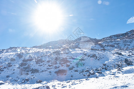 冬日阳光在积雪顶部的太阳覆盖喜马拉雅山脉 在寒冷的冬日 充满深雪的冰冻岩石峰照亮了升起的阳光 湛蓝晴朗的天空 没有云 通往太阳的道路 风背景