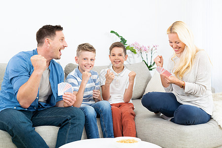 家庭在客厅沙发上玩游戏快乐 一起欢乐庆祝比赛赢家的节日活动父母爸爸妈妈竞赛父亲儿子女士庆典乐趣成人图片