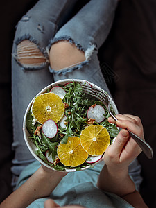 穿着牛仔裤的床上女人 拿着素食沙拉碗减肥饮食排毒菠菜女孩萝卜盘子膝盖早餐核桃图片