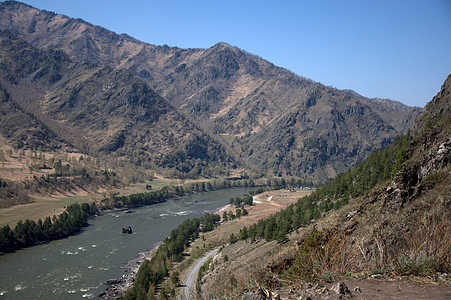 湍急的绿松石河在山脉的融合中流过山谷图片