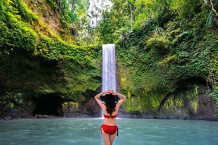 站在印度尼西亚巴厘岛Tibumana瀑布的妇女假期热带天堂森林电话游客女士旅游石头女性图片