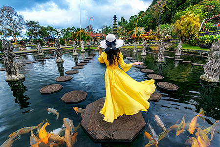 在印度尼西亚巴厘的水宫里 妇女与多彩鱼一起站在池塘中图片