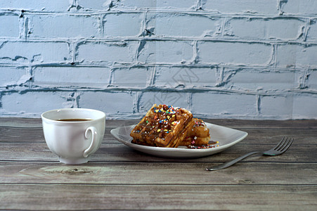 早餐 叉子 一杯黑咖啡和一张盘子 两张维也纳华夫饼放在木桌上图片