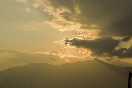 12 月中旬的一个晚上 戏剧性的深红色夕阳云使天空变得浪漫 阳光透过云层反射 而云层在印度山站的山脉上滚动或移动 轮廓季节金色气图片