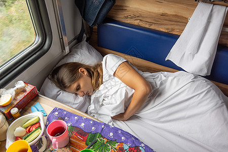 一个年轻女孩睡在火车的下铺上真实性旅行女士预留座位车皮桌子生活架子食物图片