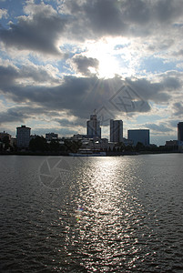 太阳的亮光从云中吹过 笼罩在河岸附近的建筑物上城市建筑商业天空全景天际日落景观旅行摩天大楼图片