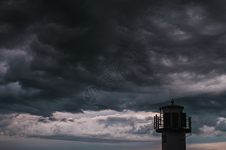 在暴风云前的灯塔灾难建筑气候力量海岸线石头支撑天空日落危险图片