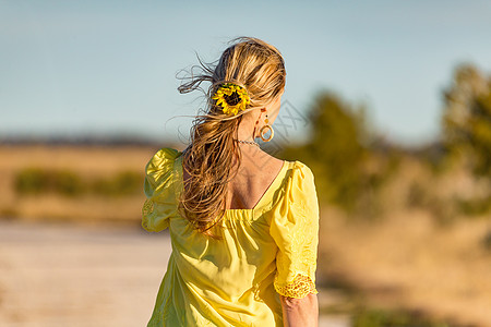 女人在阳光向日葵中户外 她的长发图片