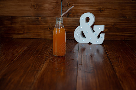 一个老酒瓶 新鲜的压榨果汁 在木制背景 和发光的安培剂图片