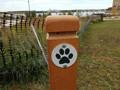 在有草的狗公园橙色柱子上的狗爪标志图片