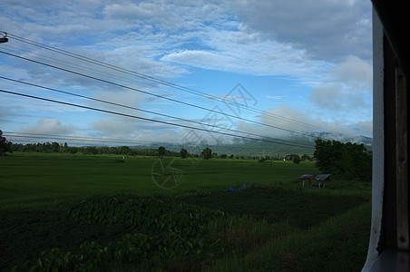 在泰国 从火车窗口观看乡村与天空运动 天气晴朗温暖海滩铁路蓝色旅行运输背包天空街道速度农村图片