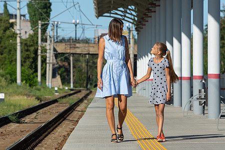 年轻美丽的女孩和少女女儿在火车站的空平台上行走 无处不在图片