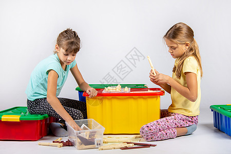 两个女孩从设计师那里 在一个大塑料盒子上收集一栋房子图片