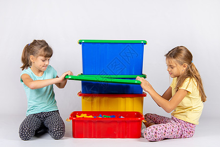 塑料闺蜜团两个女孩开了一个装玩具的大型塑料箱背景