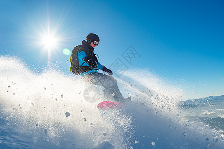 滑雪运动员在太阳尼日登上山峰红雪板 滑雪和冬季运动行动下坡乐趣粉末季节速度娱乐木板背包假期图片