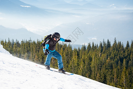 滑雪运动员在太阳尼日登上山峰的雪板 滑雪和冬季运动行动下坡单板晴天蓝色假期娱乐粉末云杉背包图片