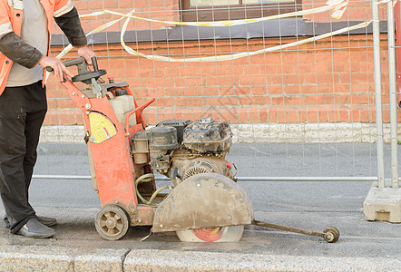 路务工人用钻石锯刀切割机器在沥青路切沥青图片