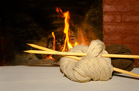 冬季概念概念 以木本为背景 用家里的火来编织羊毛和三角针火焰木头椅子经编家庭袜子针织图片