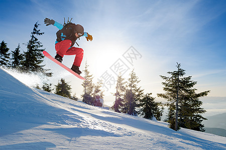 滑雪运动员在太阳尼日跳上山中红雪板 滑雪和冬季运动单板太阳木板粉末假期下坡晴天蓝色娱乐头盔图片