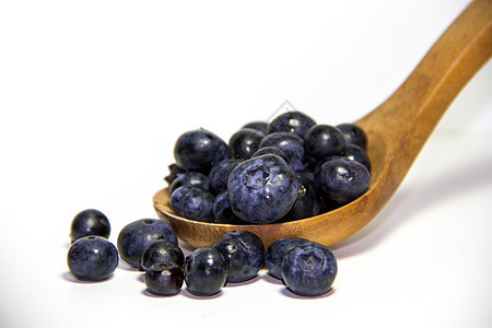 白背景和木勺子上的红水果甜点蓝色树叶食物宏观健康浆果植物营养采摘图片