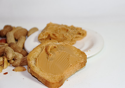 白底带花生酱的吐司面包奶油状小吃营养午餐桌子食物棕色花生早餐图片