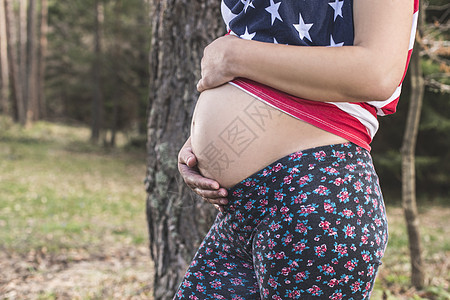 森林中的孕妇女性生育力母亲公园怀孕父母绿色森林喜悦腹部图片