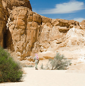 贝都因人在埃及沙漠峡谷的岩石中行走异国季节旅行蓝天白云山脉石头山顶衬套蓝色背景图片