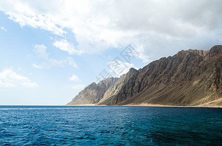 蓝海和高岩山 与天空和乌云相对山脉支撑地平线旅行岩石海岸海景石头蓝色旅游图片