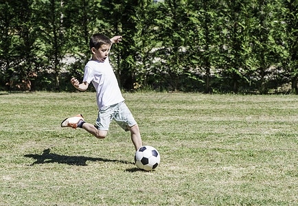 儿童在体育场踢足球行动游戏乐趣公园场地活动绿色跑步运动水平图片