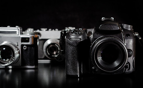 两台古老的摄像机 和一台现代相机 在黑色背景上图片