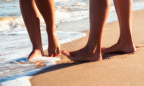 海浪中沙滩上的雌性脚 在海浪的波浪中天堂支撑女孩海洋气候女士棕褐色假期皮肤海岸图片