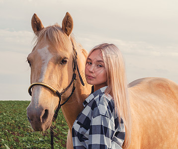 一个年轻金发女孩的肖像 在牧场上骑着米蜂蜜马草地友谊毛皮蓝色场地动物金发女郎植物绿色村庄图片
