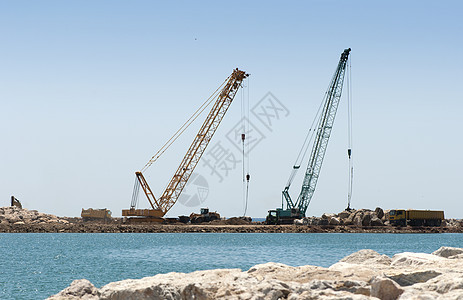 起重车和挖土机投掷石块水路天空海滩建筑学工程石头挖掘机安全灾难海浪图片