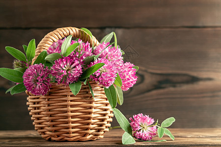 夏天早上 在木桌边的圆篮子上 盛装着粉红色的花朵图片