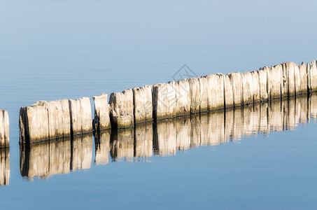 下午在湖的平静水中 堆积着木凳景色背景蓝色池塘水面柱子气候季节波浪树桩图片