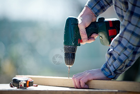 一个用电动螺丝刀工作的木匠建筑工的手图片